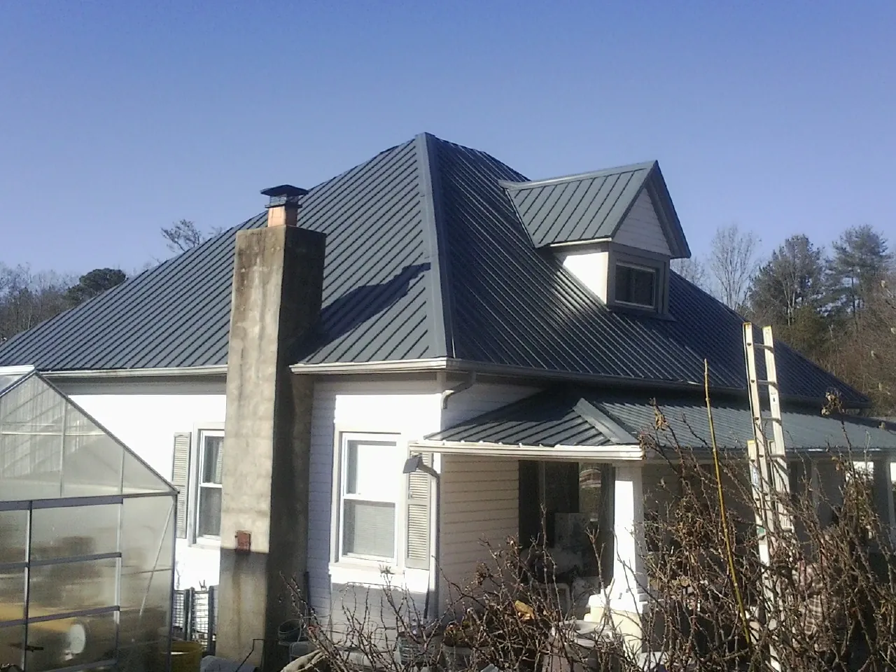 Dark blue standing seam metal roof on a white farmhouse with dormer — Slate & Tile Roof Repair by Roofing Brothers in Ipswich