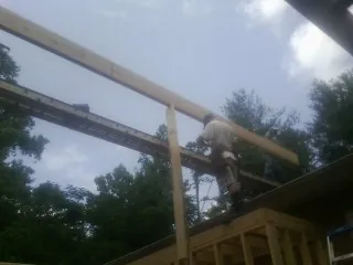 Carpenter setting a ridge beam over a new addition frame — Ice Dam Removal by Roofing Brothers in Ipswich