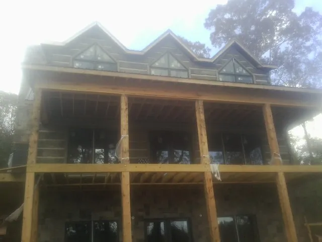 Dormers and porch framing on a large log home under construction — Roof Coating work by our crew in Ipswich