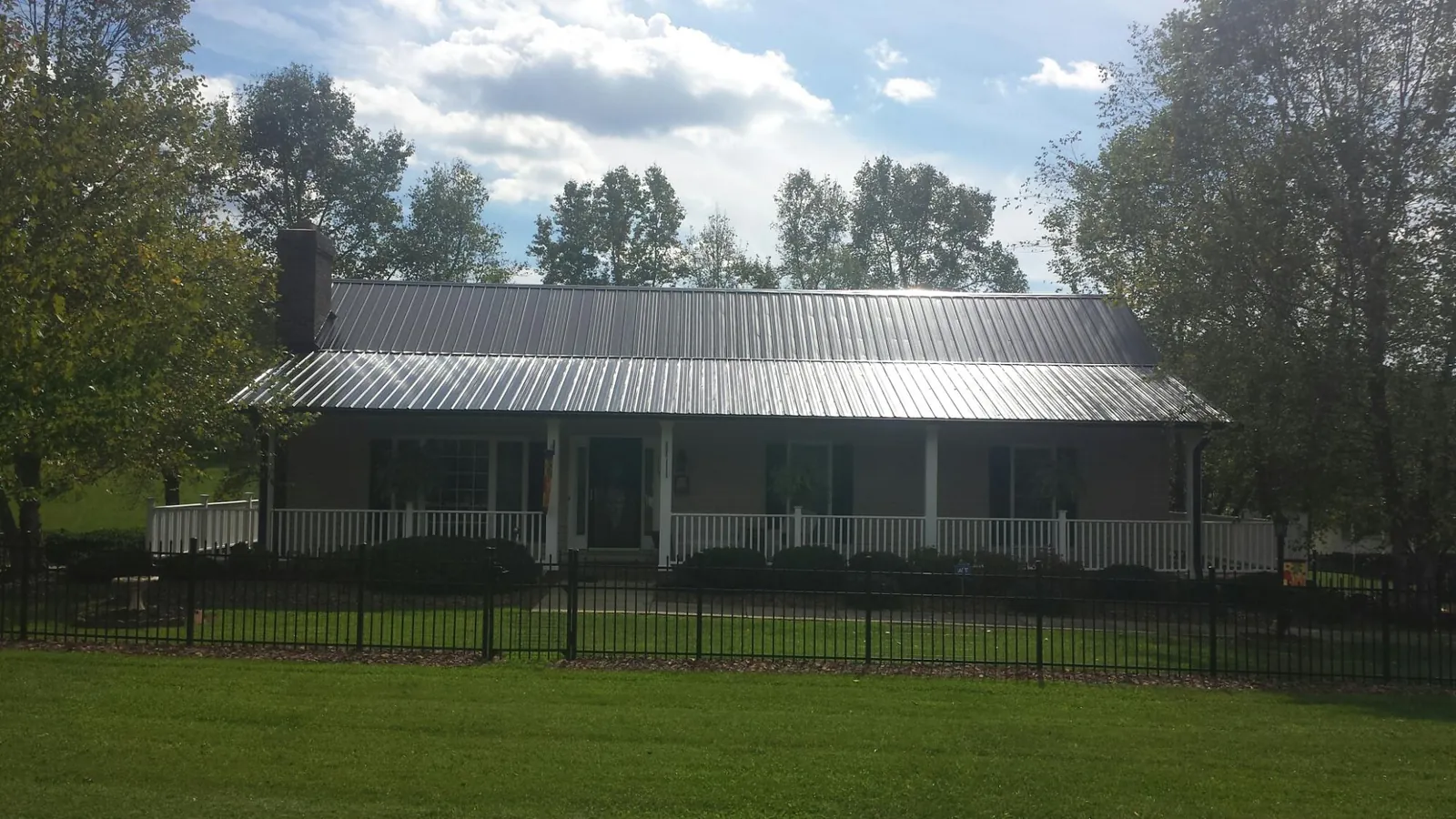 Gray metal roof on a brick ranch with a full width front porch — Gutter Guard Installation work by our crew in Ipswich